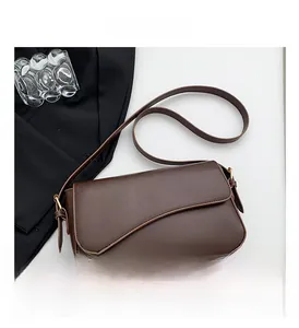Detail of dark brown matte leather shoulder bag with irregular wave flap and gold hardware