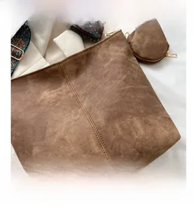 Detail of brown suede bucket bag featuring ethnic floral print strap and contrast stitching