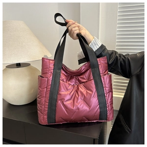 Detail of dark plum quilted tote bag featuring metallic finish and thick nylon handles