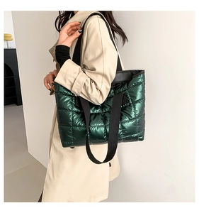 Detail of dark green quilted tote bag with shiny finish and black shoulder straps