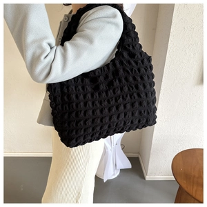 Detail of black ruched bubble texture shoulder bag styled with a neutral casual outfit