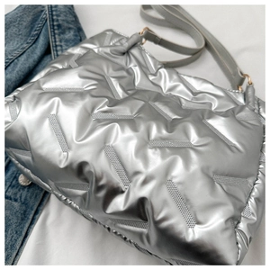 Détail d'un sac cabas argenté matelassé avec fini métallisé et anneaux dorés brillants