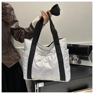 Detail of silver quilted puffer tote bag in office setting with wide shoulder strap