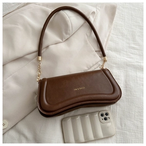 Detailed close-up of dark brown faux leather shoulder bag with wavy curved design and gold chain