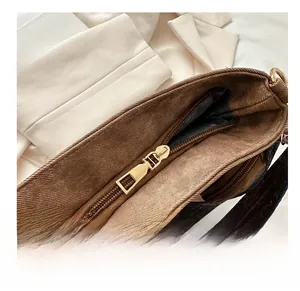 Close-up of golden metal zipper detail and smooth closure on a brown fabric bucket bag