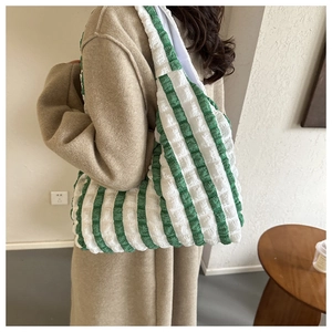 Detailed texture of green and white striped pleated fabric on a large tote bag