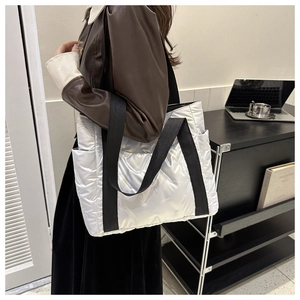 Detail view of silver quilted tote bag with black strap and puffy diamond pattern texture