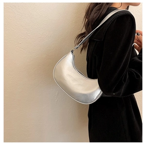 Silver metallic crescent underarm bag shown with a black velvet outfit for contrast