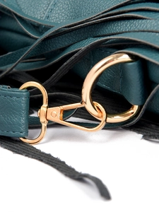 Detail of dark green pebble leather bag with gold metal rings and black leather tassels