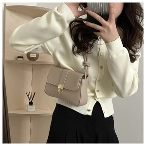 Detail of beige leather crossbody bag featuring gold vintage lock and knot strap detail