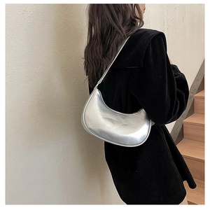 Side view of a silver metallic hobo shoulder bag with a sleek minimalist half-moon shape