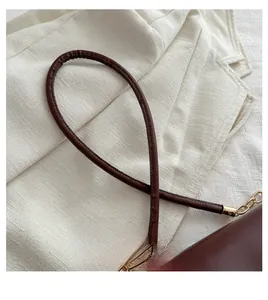 Detail of deep brown leather handle with golden hardware chain on a retro handbag