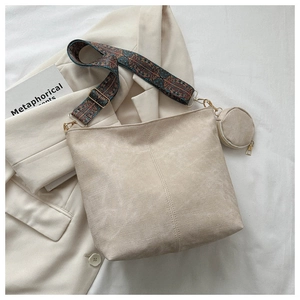 Detail of beige suede bucket bag with bohemian strap and round coin purse attachment