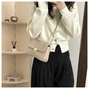 Detail of beige flap crossbody bag with a vintage gold metal lock and leather texture