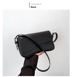 Detail view of the black flap shoulder bag with gold hardware and a slender strap