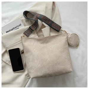 Detail of minimalist bucket bag with embroidered wide strap and round coin purse accessory