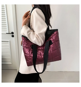 Close-up of quilted burgundy tote bag featuring metallic gloss finish and wide straps