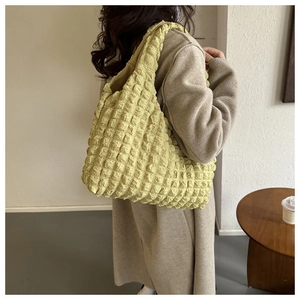 Close-up of avocado green bubble tote bag with popcorn texture and elastic shoulder strap