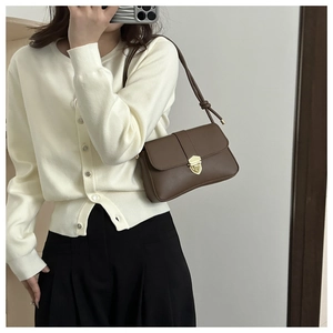 Brown leather crossbody bag with gold lock buckle and knot strap detail shown on model