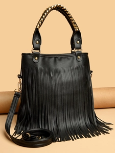 Detail of lychee textured leather surface and long tassel on a black fashion handbag
