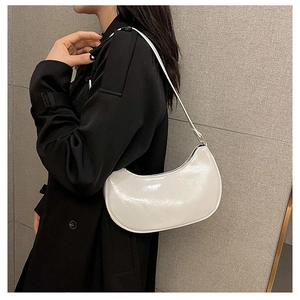 Detail view of the white glossy pearlescent baguette bag worn on a woman's shoulder