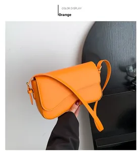 Detail of orange flap shoulder bag with curved cut and adjustable strap