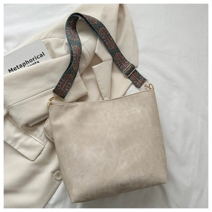 Detail of beige corduroy bucket bag featuring bohemian patterned wide shoulder strap