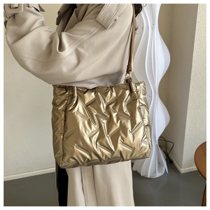 Détail de la texture d'un sac cabas matelassé doré brillant avec une bandoulière marron