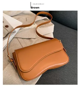 Detail of a brown faux leather shoulder bag with gold buckle and adjustable strap