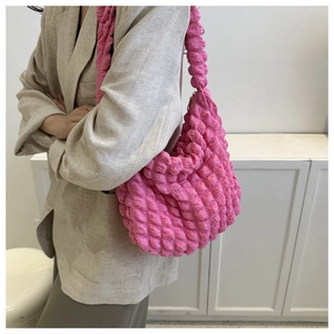 Detail view of hot pink bubble textured shoulder bag with wide strap on model