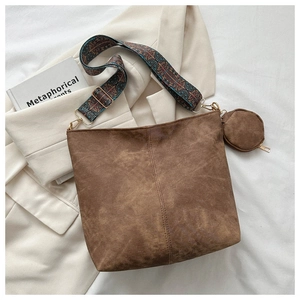 Detail of brown suede bucket bag with geometric wide strap and small round coin purse pouch