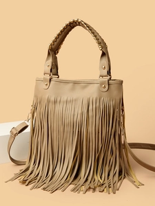 Detail of khaki tassel handbag with golden cone studs and adjustable strap on a minimalist base