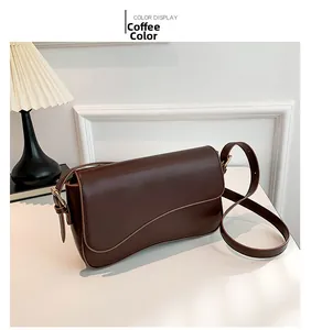 Detail of a dark brown crossbody bag with irregular flap design on a minimalist background