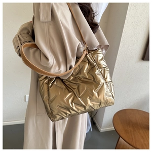 Gros plan du sac cabas matelassé doré métallisé avec ses anses en cuir marron robustes
