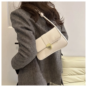 Close-up of cream leather shoulder bag with vintage gold buckle on grey wool blazer