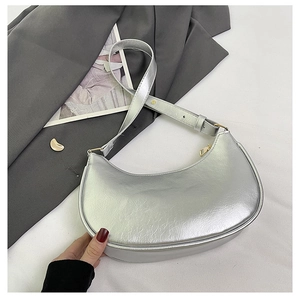 Detail of silver crescent hobo bag with metallic cracked texture on a gray suit background