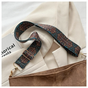 Detail of wide ethnic style canvas strap with geometric patterns and gold metal hooks