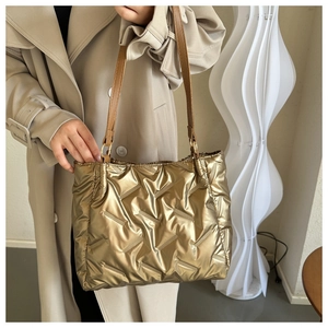 Détail d'un grand sac cabas doré matelassé avec finitions métalliques brillantes
