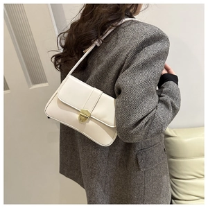 Classic cream crossbody flap bag with gold clasp shown styled on a grey blazer outfit