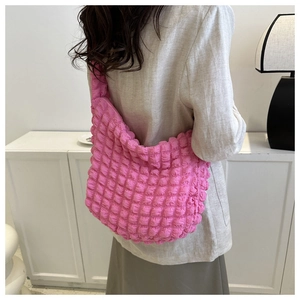 Detail of pink bubble texture pleated shoulder bag shown on a model in a minimalist room