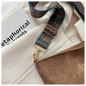 Close-up of vintage brown bucket bag with colorful ethnic style woven shoulder strap