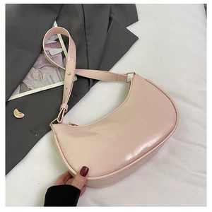Detail of light pink crescent underarm bag with glossy finish and gold zipper closure