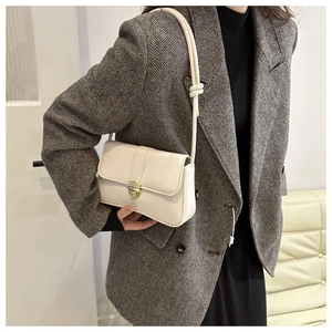 Detailed view of cream leather flap bag with gold clasp and unique knotted shoulder strap