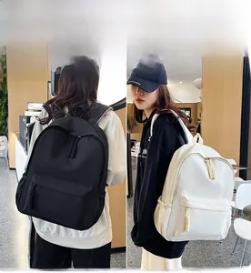 Detail view of large nylon backpacks in black and beige with braided rope zipper pulls