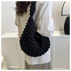 Close-up of black popcorn fabric texture on a stylish ruched cloud shoulder bag