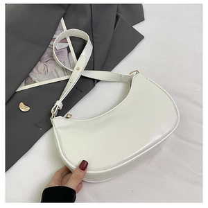 Detail of white glossy underarm bag with gold hardware and slim adjustable strap