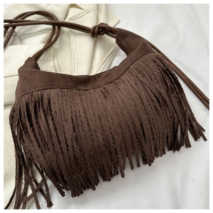 Close-up of dark brown suede fringe shoulder bag with bohemian tassel design details