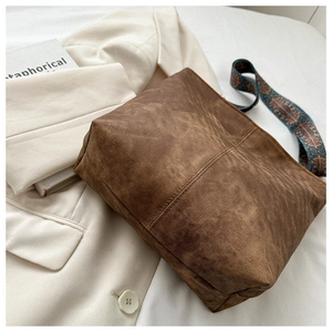 Close-up of retro brown bucket bag with textured surface and patterned ethnic strap