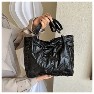 Gros plan du sac cabas matelassé noir avec poignées en cuir et anneaux métalliques dorés