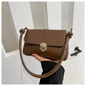 Detail of a brown leather shoulder bag featuring a gold shield buckle and knotted strap